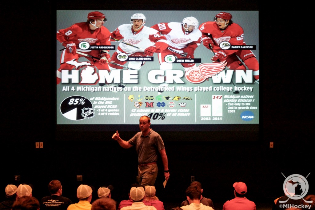 Grand Rapids Griffins coach Jeff Blashill stands in front of an infographic spelling out Michigan's college hockey successes. (Photo by Michael Caples/MiHockey)