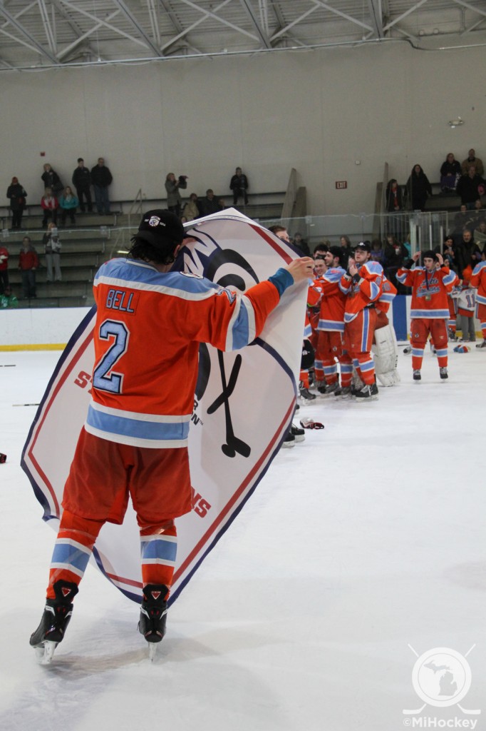 Evan Bell carrying a state championship banner for his Little Caesars Midget Major team in 2014. (Photo by Michael Caples/MiHockey)